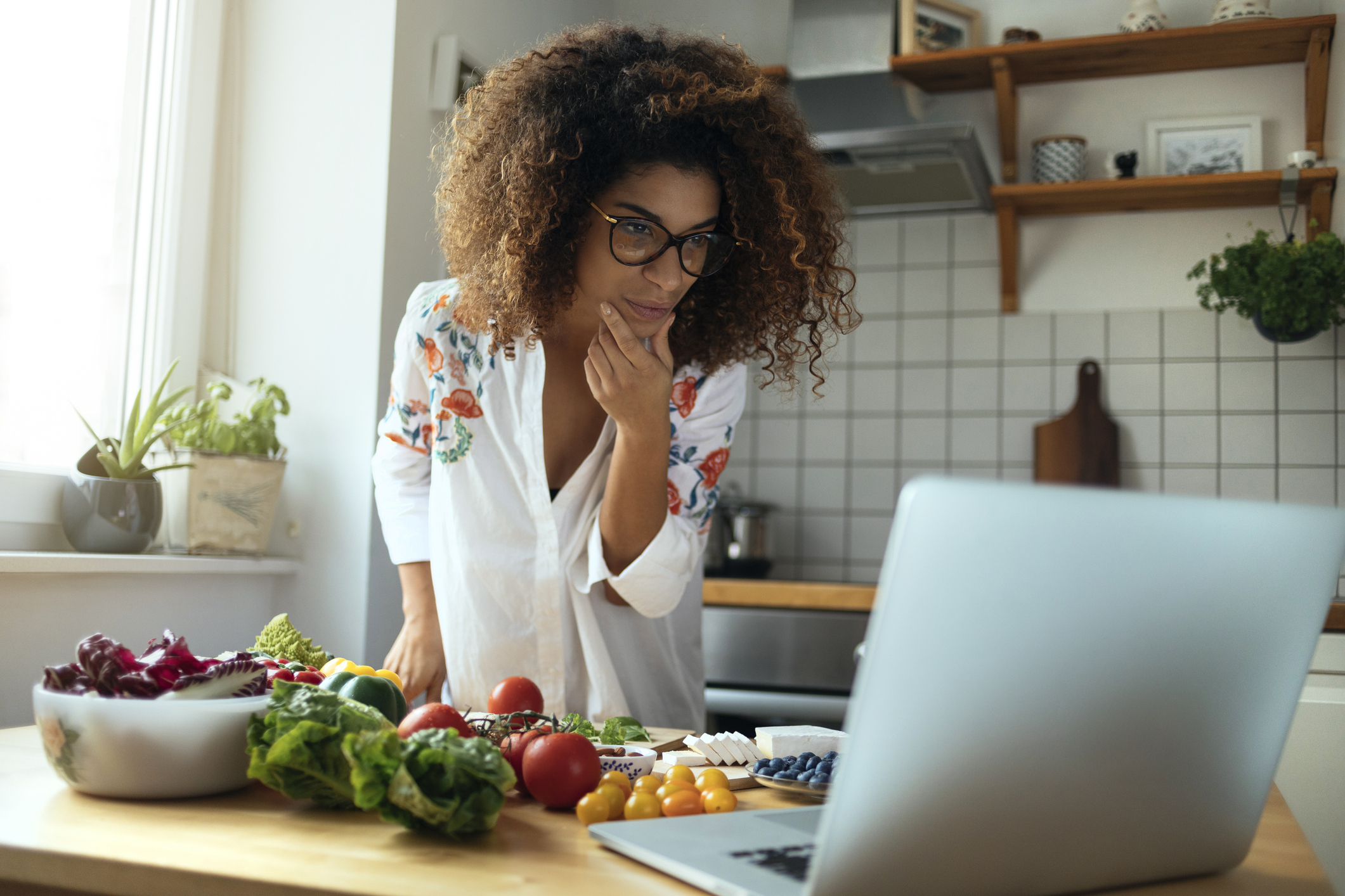 Woman in her kitchen looking at her computer for keto diet recipe ideas.